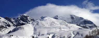 Piste kayak pisti dışında ve güneşli kış gününde bulutların içinde karlı dağlar. Kafkasya Dağları, Tetnuldi Dağı, Gürcistan 'ın Svaneti bölgesi. Panoramik görünüm.