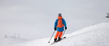 Kar yamaçlarında tepeden aşağı kayak yapan ve kar fırtınasından önce bulutlu gökyüzü, kötü hava koşullarıyla kaplanıyordu. Kışın Kafkasya Dağları, Gürcistan, Gudauri bölgesi. Panoramik görünüm.