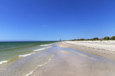 Açık deniz, kumsal, mavi gökyüzü ve güneş yaz gününde iki deniz feneri. Geniş açı görünümü.