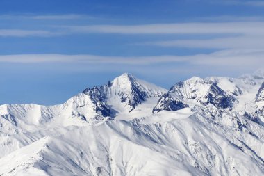 Yüksek karlı dağlar ve soğuk kış gününde bulutlu mavi gökyüzü. Kafkasya Dağları, Gürcistan bölgesi Gudauri.