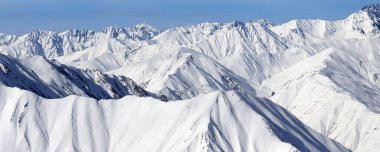Yüksek karlı dağlarda panoramik manzara ve güneşli kış gününde bulutlu mavi gökyüzü. Kafkasya Dağları, Gürcistan bölgesi Gudauri.