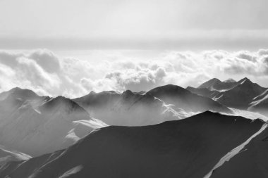 Akşam güneşinin silueti sisli karlı dağlarda. Kafkasya Dağları, Gürcistan, kışın Gudauri bölgesi. Siyah ve beyaz tonlu manzara