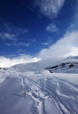 Akşamları yüksek kış dağlarında kayak ve snowboard izleri olan karlı bir yokuş. Kafkasya Dağları, Gürcistan, Gudauri bölgesi. 
