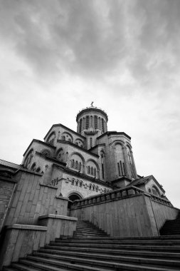 Tsminda Sameba Katedrali ya da Kutsal Üçlü Katedrali ve bulutlu gri gökyüzü. Gürcistan 'ın başkenti Tiflis' teki Gürcistan Ortodoks Kilisesi 'nin ana katedrali. Siyah ve beyaz geniş açı. Yüksek karşıtlık