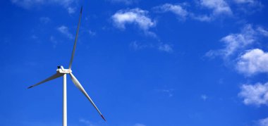 Rüzgar türbini ve güneş gününde bulutlu mavi gökyüzü. Panoramik görünüm.