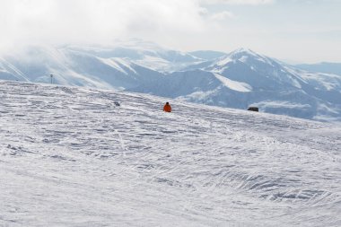 Kar pisti yamacında yokuş aşağı kayakçı ve kış sabahı puslu dağlarda kayakçı. Kafkasya Dağları, Gürcistan, Gudauri bölgesi.