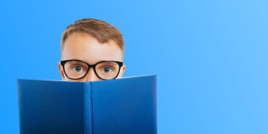 Çocuk parlak bir duvara karşı kitap okuyor.