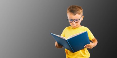 Çocuk parlak bir duvara karşı kitap okuyor.