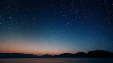 Gece gökyüzünde dağların manzarasıyla yıldızların hareketi