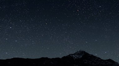 Bir dağ. Arkaplan gece gökyüzü yıldızlar, ay ve bulutlarla...