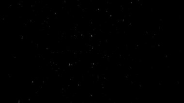 Siyah arka planda yavaş yavaş kar yağıyor.