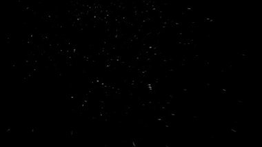 Siyah arka planda yavaş yavaş kar yağıyor.