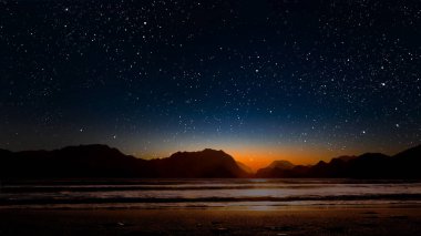 Gece gökyüzünde dağların manzaralı bir yıldız hareketi...