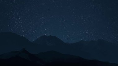 Gece gökyüzünde dağların manzaralı bir yıldız hareketi..