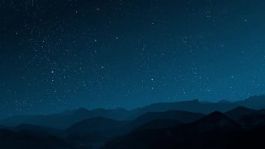 Gece gökyüzünde dağların manzaralı bir yıldız hareketi..