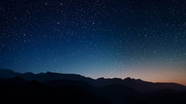 Gece gökyüzünde dağların manzaralı bir yıldız hareketi..