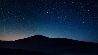 Gece gökyüzünde dağların manzaralı bir yıldız hareketi..