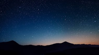 Gece gökyüzünde dağların manzaralı bir yıldız hareketi..