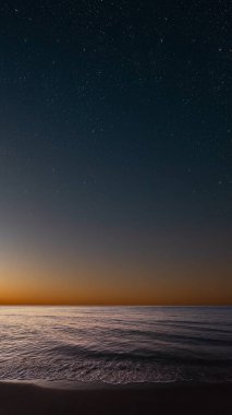 Denizin üzerinde gün doğumu, yumuşak dalgalar ve solgun yıldızlar huzur içinde.
