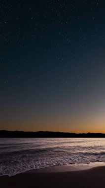 Denizin üzerinde gün doğumu, yumuşak dalgalar ve solgun yıldızlar huzur içinde.