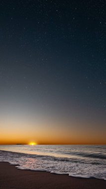 Denizin üzerinde gün doğumu, yumuşak dalgalar ve solgun yıldızlar huzur içinde.