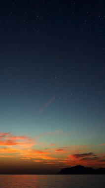 Denizin üzerinde gün doğumu, yumuşak dalgalar ve solgun yıldızlar huzur içinde.