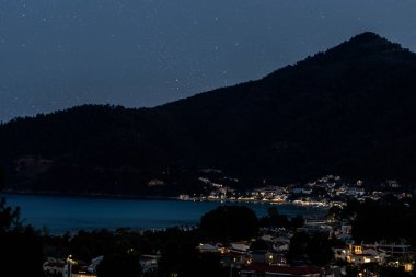 Deniz kıyısında bir dağ kasabası Yıldızlı bir gece gökyüzünün altında.