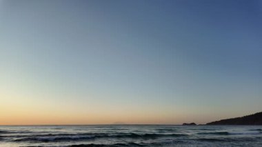 Sahilde gün doğumu sakin ve dalgalı