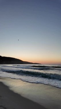 Sahilde gün doğumu sakin ve dalgalı