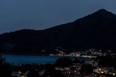 Deniz kıyısında bir dağ kasabası Yıldızlı bir gece gökyüzünün altında.