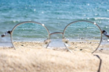 Güneşli bir sahilde, gözlüklerden açık deniz manzarası..