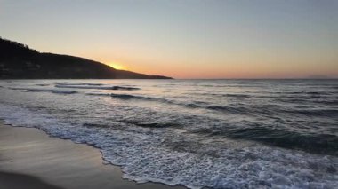 Sahilde gün doğumu sakin ve dalgalı