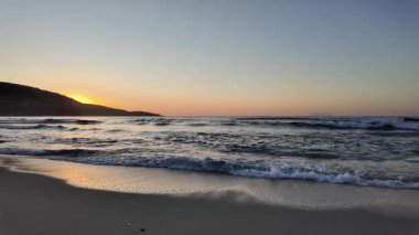 Sahilde gün doğumu sakin ve dalgalı