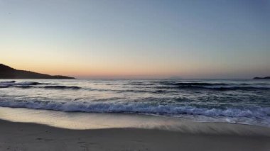 Sahilde gündoğumu sakin ve dalgalı. 