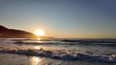 Sahilde gündoğumu sakin ve dalgalı. 