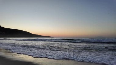 Sahilde gündoğumu sakin ve dalgalı. 