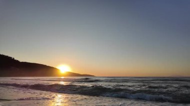 Sahilde gündoğumu sakin ve dalgalı. 