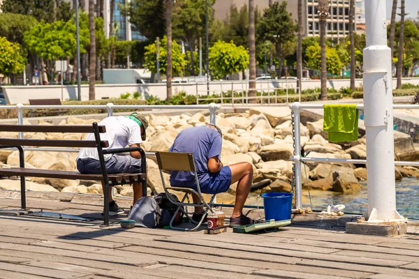 两名渔民坐在长椅上 坐在木制码头的折叠椅上 准备捕鱼用的设备 — 图库照片