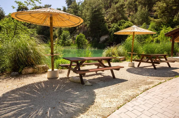 山地池塘有木制桌子 长椅和雨伞的野餐场所 — 图库照片