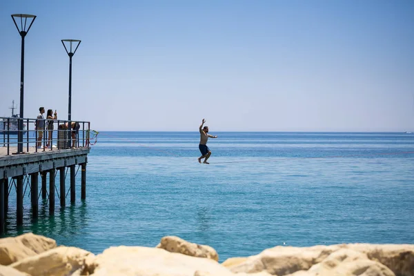 リマソル キプロス 2021年7月9日 海の上のロープを歩いている未確認の若者 他の人がスマートフォンで写真を撮る — ストック写真
