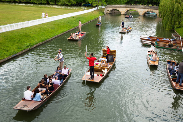 Cambridge, UK - June 2, 2022 - Punting tour along the both sides of river Cam, historic buildings and colleges.