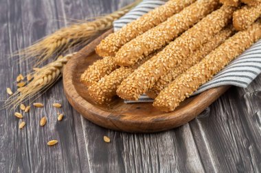 Tahta tepside susam tohumlu ekmek hastaları. Buğday kulakları ve tahıllar.