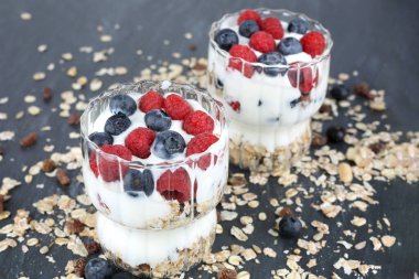 Arka planda iki bardak içinde ahududu ve yaban mersinli Muesly..