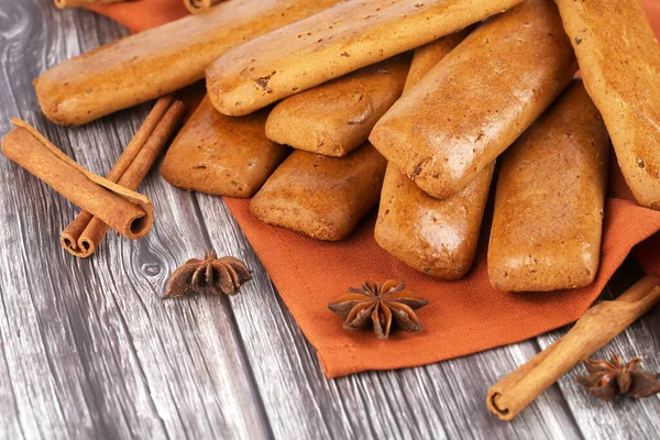 Cookies with anise and cinnamon sticks on brown cloth on wooden table.