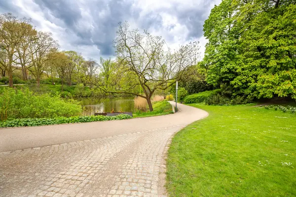 stock image Hamburg urban park Planten un Blomen, Plants and Flowers in English. Pond, blue sky, gray clouds, field with flowers, trees in the city park. 