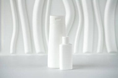 Beyaz arka planda iki beyaz cilt bakım ürünü var. Beyaz üzerine kozmetik şişeler.