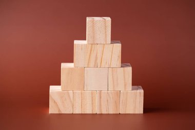 Kırmızı arka planda izole edilmiş pek çok küçük tahta küp var. Güzel desenli küçük küplerden yapılmış tahta küp piramidi..