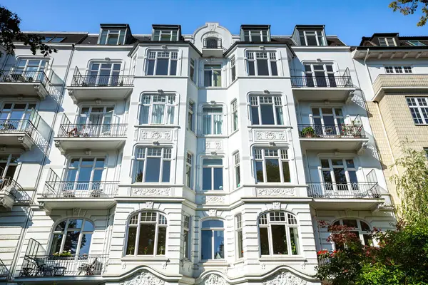 Duvarlarında muhteşem süslemeler olan beyaz konut binası. Binadaki ağaçlar.