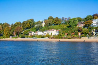 Hamburg, Almanya 'daki güzel nehir manzarası. Elbe Nehri 'nin manzarası. Lüks evler ve kumsalda yeşil ağaçlar..