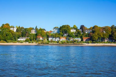 Hamburg, Almanya 'daki güzel nehir manzarası. Elbe Nehri 'nin manzarası. Lüks evler ve kumsalda yeşil ağaçlar..
